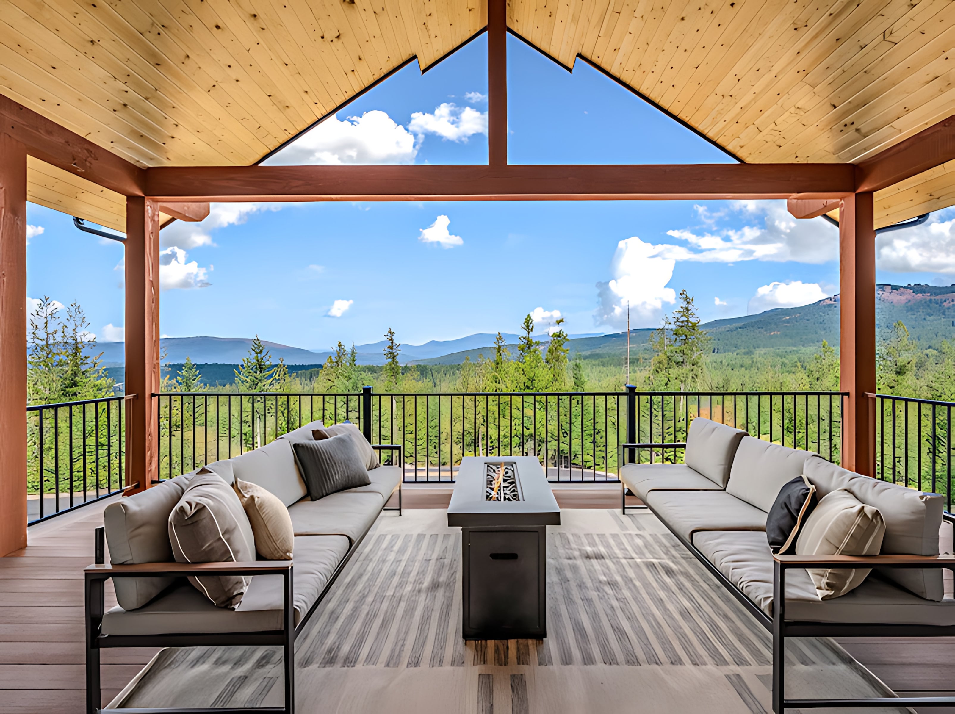 Covered timber deck with a fire pit table overlooking forested North Idaho mountains at an ONYX custom home